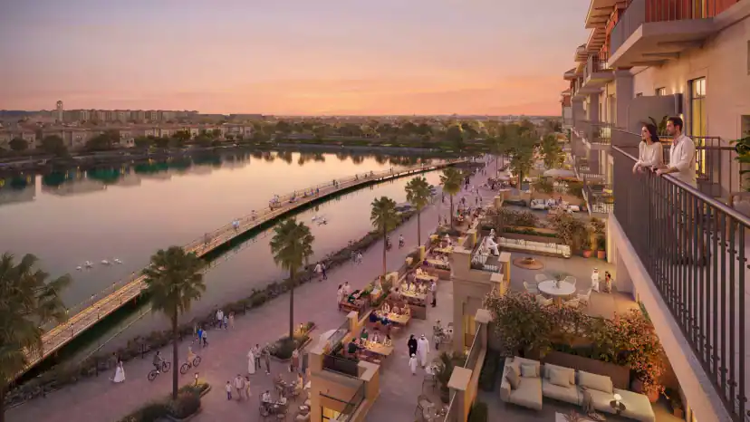 Rendering at sunset of a waterfront promenade seen from a balcony, with two people at the railing, restaurant terraces, palm trees, cyclists, and a boardwalk over the water.