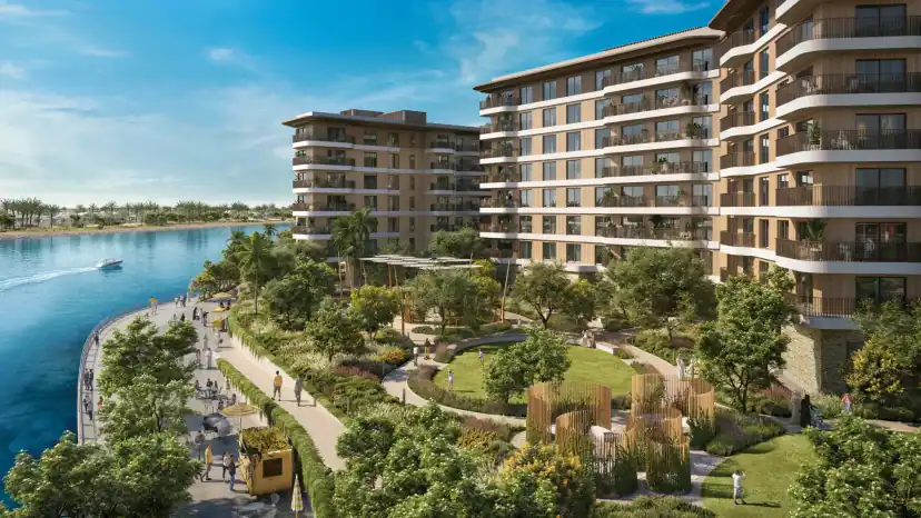 Rendering of apartment buildings with wraparound balconies overlooking a landscaped lawn and a waterside walkway where people are walking, with water on the left.
