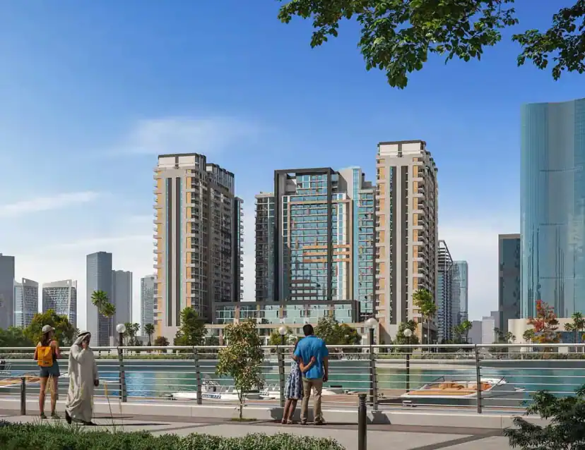 Rendering of tall apartment towers beside a waterfront promenade with a railing, where three pedestrians stand near boats moored on the water.