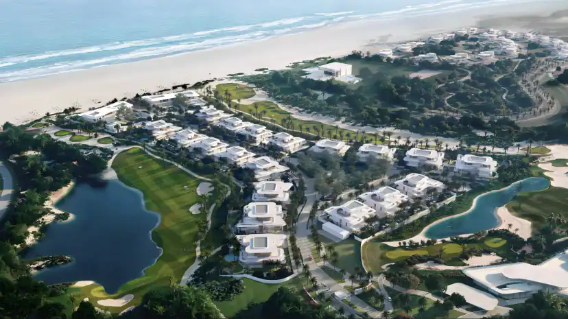Aerial rendering of white modern villas with flat roofs along a beach, with a golf course, a lagoon, sand areas and landscaped paths between the buildings.