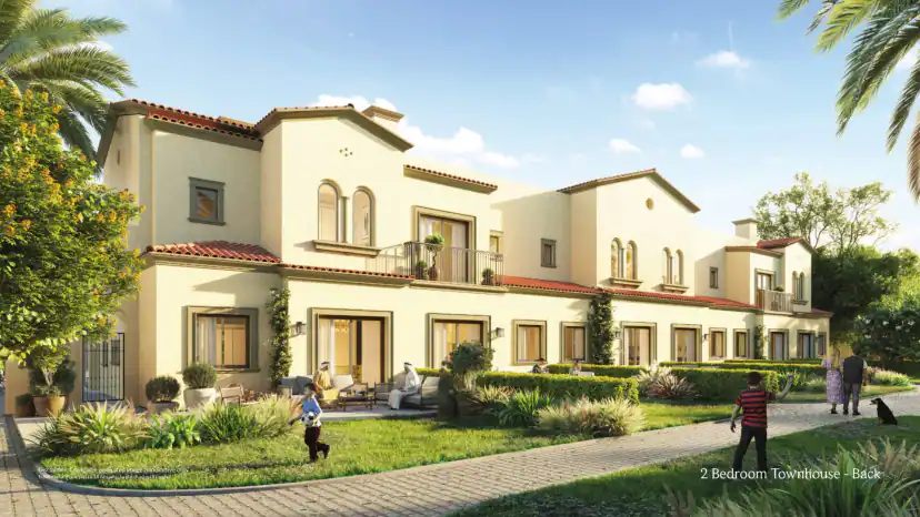 Rendering of the rear of a two-storey townhouse row with a lawn, hedges, a paved path and people sitting on a patio and walking.